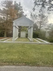 The image shows an elegant, classical-style family mausoleum with the name 