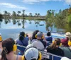 Passengers wearing protective ear gear are on a boat tour likely an airboat ride enjoying the tranquil waters and scenic view of a natural landscape possibly a swamp or wetland area