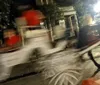 The image shows a blurred scene on a street at night with a house in the background creating a sense of motion likely from a moving vehicle or camera shake
