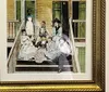 The image shows a framed colorized photograph of a group of seven people likely a family posing together on a wooden porch conveying a vintage ambiance