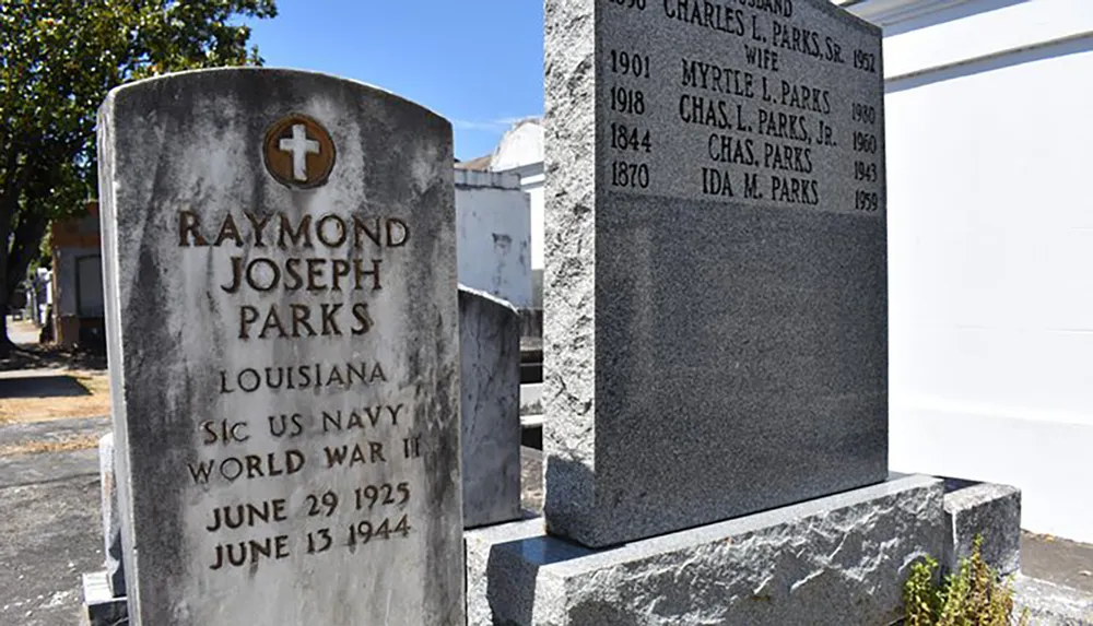 The image shows two gravestones with the left one bearing the name Raymond Joseph Parks a World War II US Navy serviceman and the right one listing members of the Parks family with their respective years of birth and death