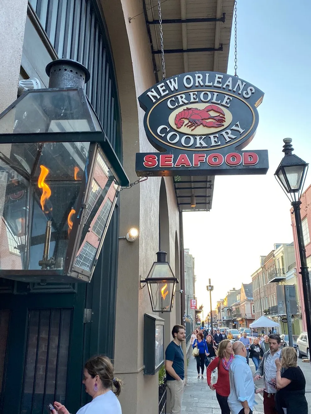 The image shows a bustling street scene with pedestrians and a prominent sign for the New Orleans Creole Cookery Seafood restaurant highlighting the areas culinary offerings