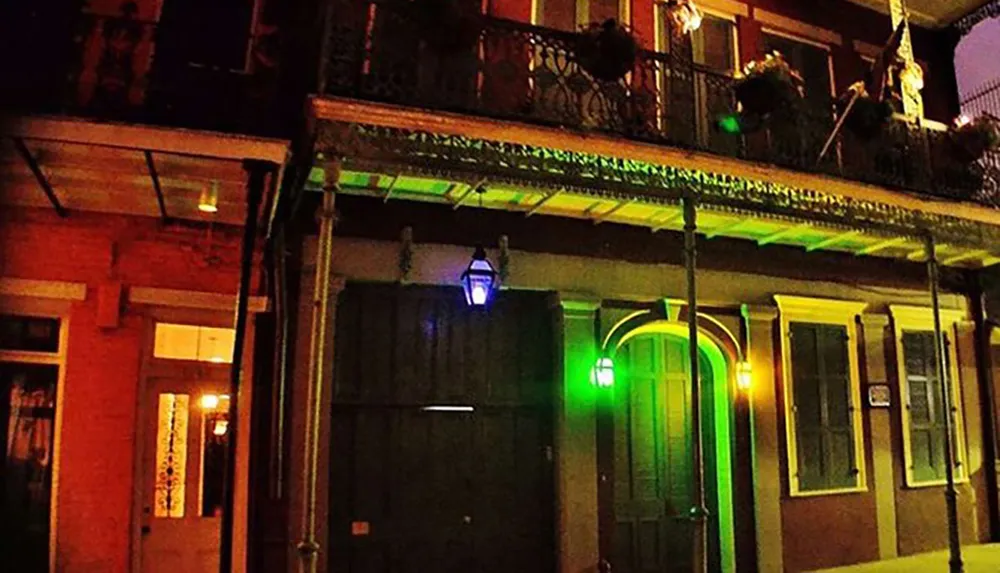 The image shows a colorful nighttime scene of a historic building with a balcony and brightly colored lights in the French Quarter of New Orleans