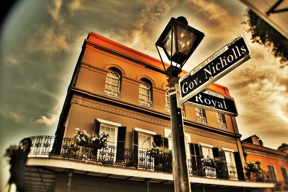 A sepia-toned photo captures a street corner with a vintage street lamp and signs for Gov Nicholls and Royal set against a classical building with a wrought-iron balcony and flower boxes under a moody sky