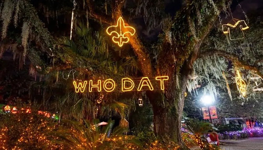The image shows a nighttime scene with a large tree adorned with yellow neon signs that read WHODAT and other symbols likely festive decorations set against a backdrop of hanging Spanish moss