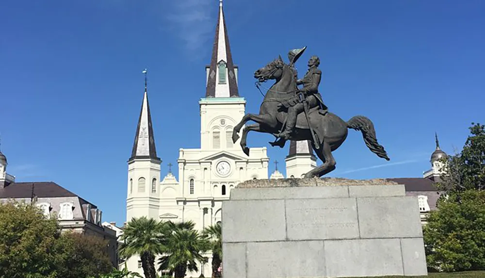 This image features an equestrian statue in front of a cathedral with two steeples against a clear blue sky