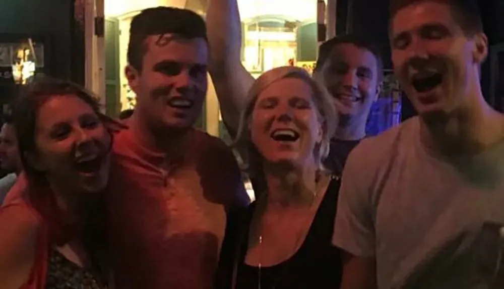 A group of five joyful people posing for a photo with big smiles possibly during a night out