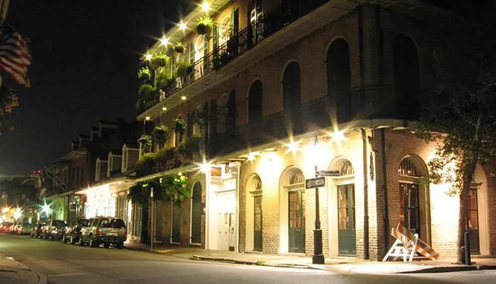 The image shows a night-time scene of a quiet historic urban street lined with classic buildings and illuminated by streetlights with an American flag hanging from a balcony