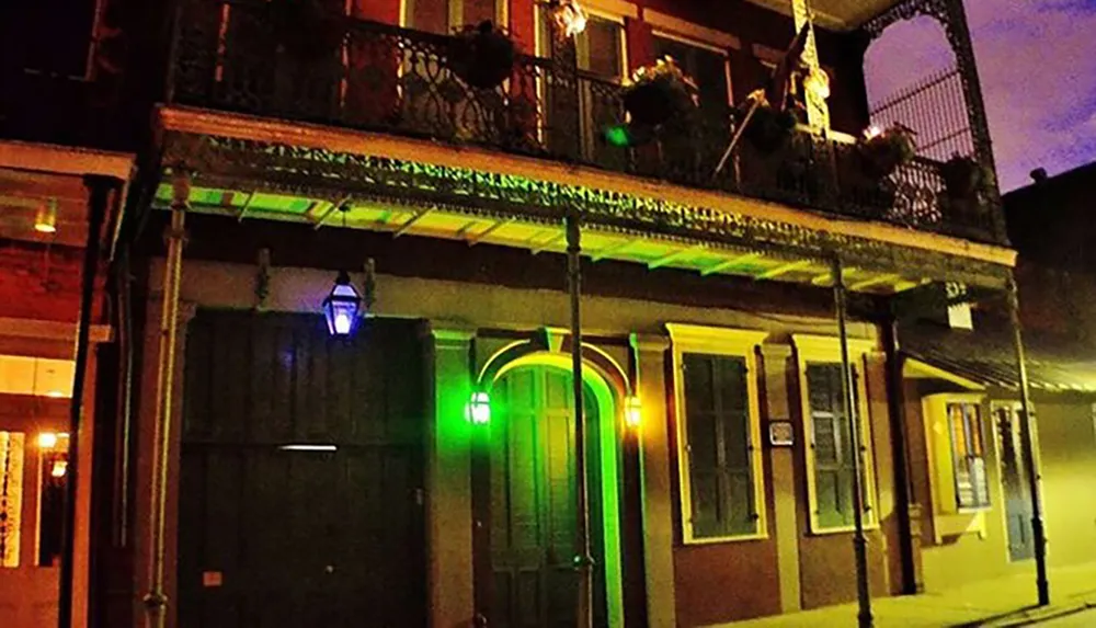 The image showcases a two-story building with a classic balcony illuminated by a distinctive green light at night evoking the atmospheric charm of New Orleans French Quarter