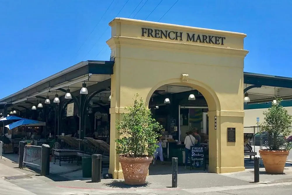 The image shows the entrance to the French Market with an archway outdoor seating and people browsing inside