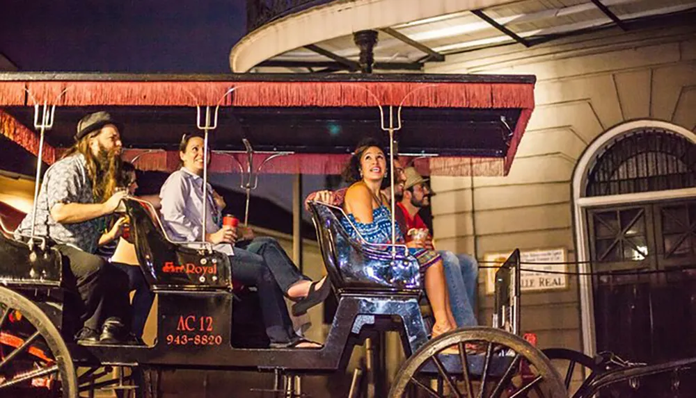 A group of people is enjoying a night out on what appears to be a pedal-powered party bike cruising through an urban street setting
