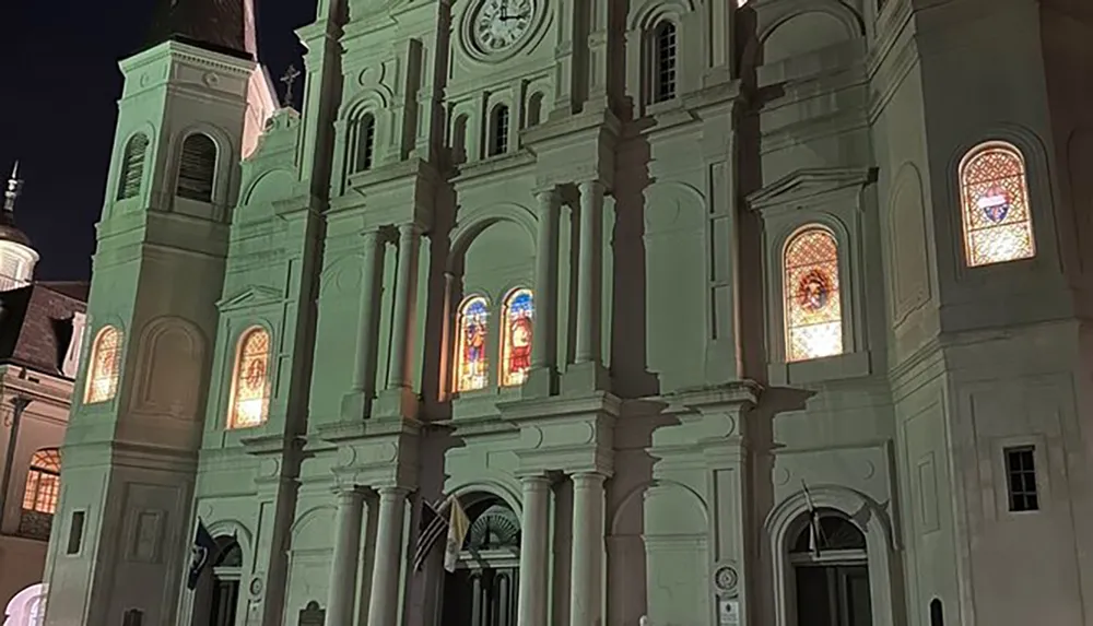 The image showcases the illuminated facade of a historic church at night highlighting its architectural details and stained glass windows