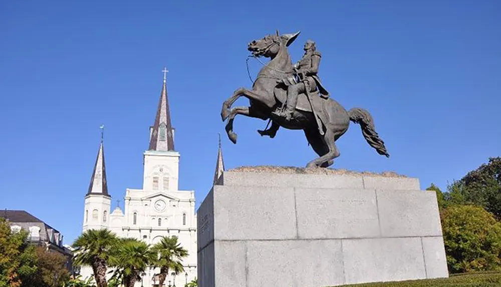 This image features an equestrian statue prominently displayed in front of a historic church with two spires under a clear blue sky