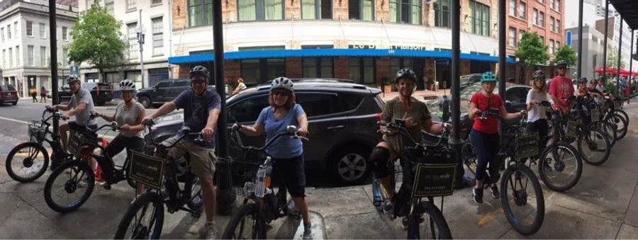 A group of people wearing helmets are standing with their bicycles on a city street, ready for a biking activity.