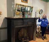 A tour guide is explaining features of a historical room with a decorative fireplace mantel objects and a mirror reflecting the scene
