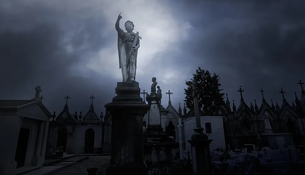 The image shows a statue of an angel pointing upwards in a graveyard with ominous dark clouds overhead creating a somber and moody atmosphere