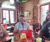 Three people are enjoying a moment of laughter and conversation at a casual dining establishment with brick walls and sports-themed decor