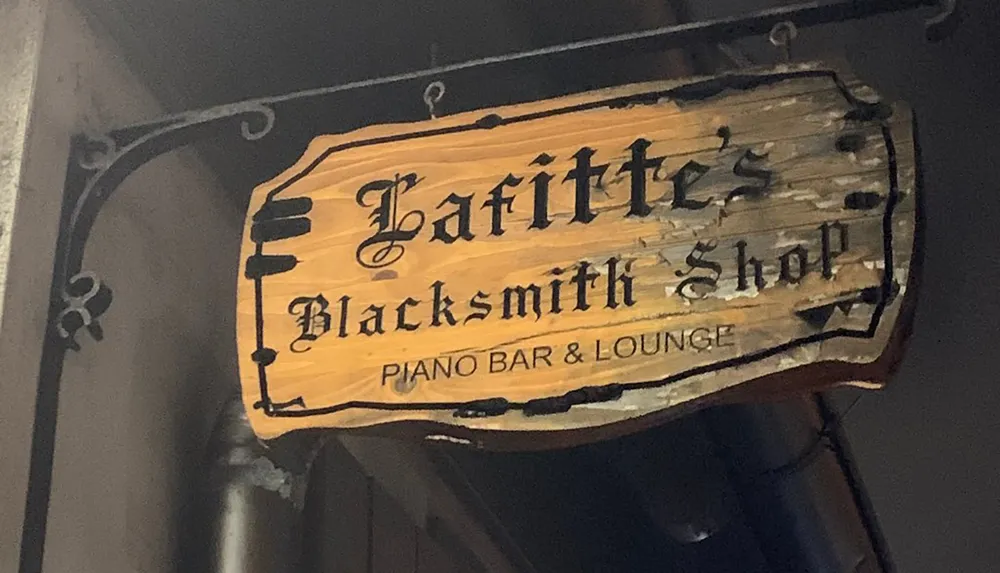 The image shows an old-fashioned weathered wooden sign for Lafittes Blacksmith Shop identified as a piano bar and lounge