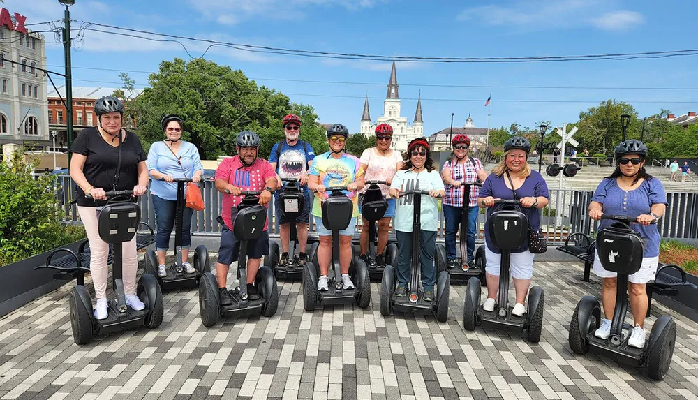 A group of people wearing helmets are posing with their Segways on a checkered path with a historic building in the background