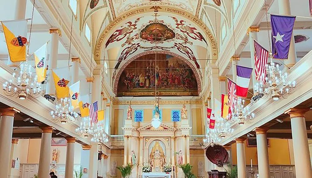 The image shows the ornate interior of a church adorned with numerous flags hung from the balcony crystal chandeliers and religious art