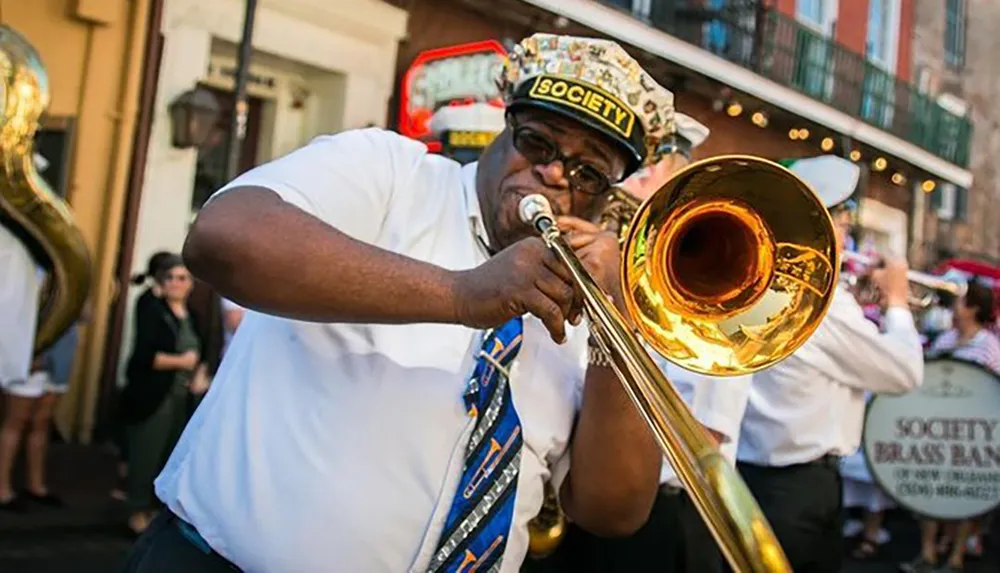 A trombonist enthusiastically plays his instrument while participating in a brass band parade on a city street
