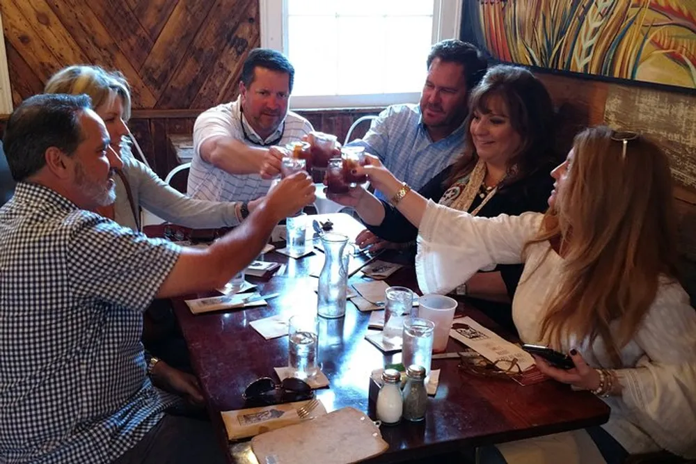A group of people are toasting with small glasses around a restaurant table