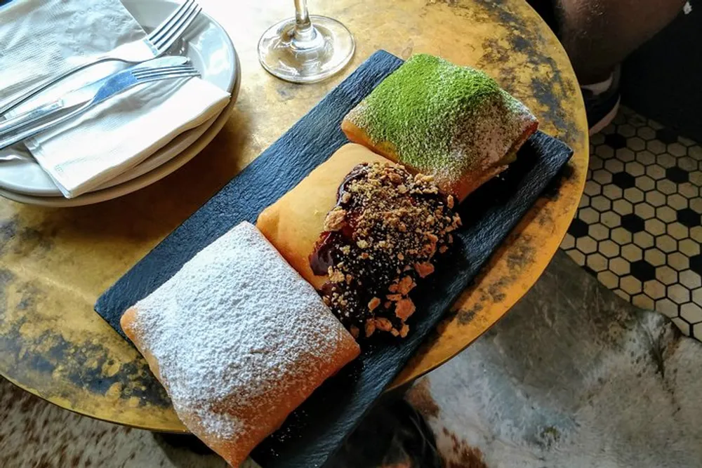 The image shows three pastries with different toppings served on a slate board on a weathered table suggesting a rustic or gourmet presentation