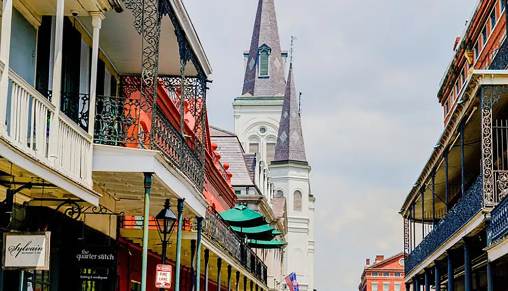 This image captures the historic charm of the French Quarter in New Orleans with its iconic wrought-iron balconies and the spire of St Louis Cathedral rising in the background