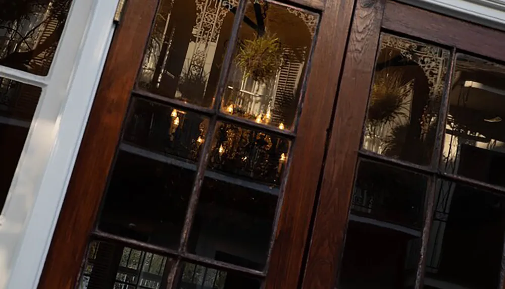 The image shows a skewed close-up view of a window pane with wooden frames reflecting an interior space with lights and decorative elements