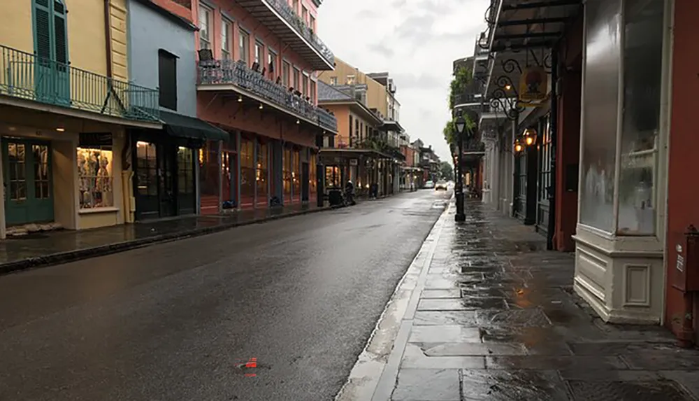 A damp street in the French Quarter of New Orleans with historic buildings reflecting the areas unique architectural style after a rain