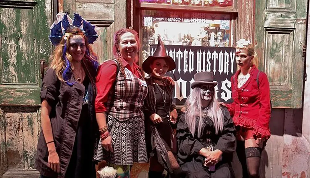 A group of people dressed in spooky and festive costumes pose together in front of a sign that reads Voodoo History Tours