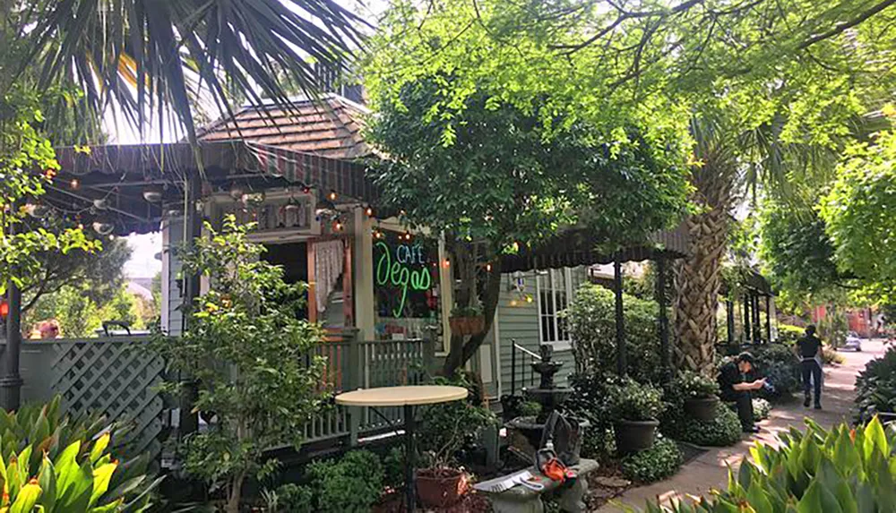 A quaint caf with outdoor seating is nestled among lush greenery and string lights creating a cozy atmosphere