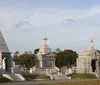 The image shows a historic cemetery with ornate mausoleums and statues highlighting the elaborate and commemorative art typical of certain graveyards