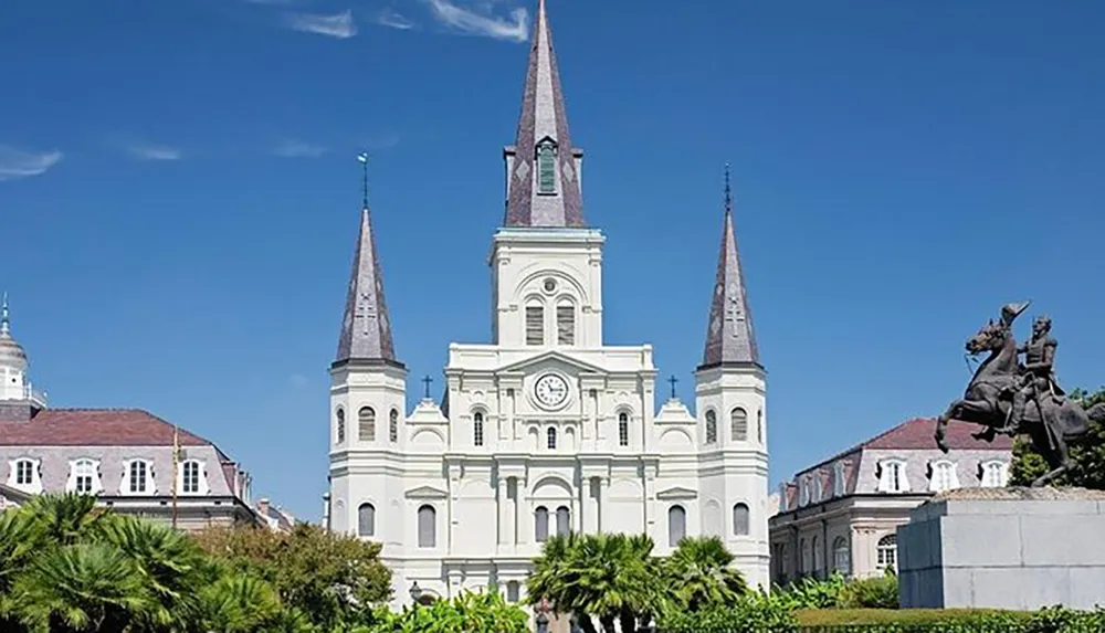 This image features the iconic St Louis Cathedral with its three spires overlooking Jackson Square in the heart of New Orleans French Quarter under a clear blue sky