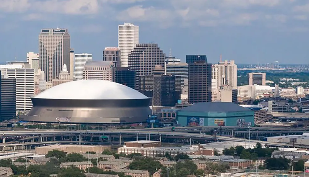The image shows a panoramic view of a citys downtown skyline with a distinctive large domed stadium in the foreground