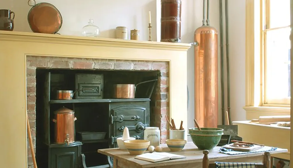 An old-fashioned kitchen featuring a wood-fired stove copper utensils and rustic pottery bathed in natural light coming through a window