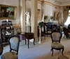 This image shows an opulent room furnished with an elegant vintage decor featuring ornate chairs classical sculptures a fireplace and elaborate artworks
