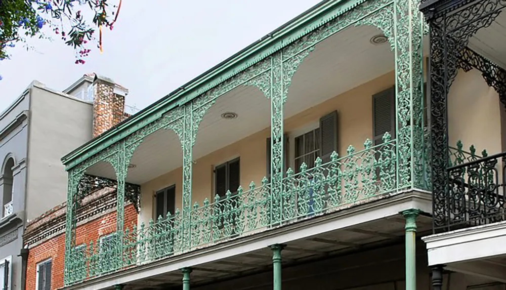 The image shows a two-story building with distinctive green wrought-iron balconies characteristic of New Orleans architectural style