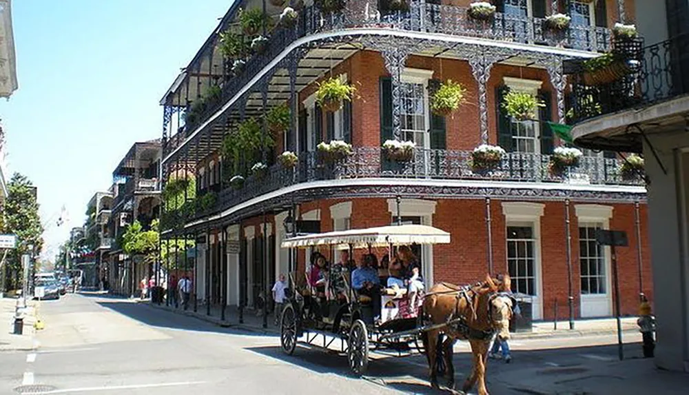 A horse-drawn carriage is passing by the distinctive wrought-iron balconies of a classic New Orleans street