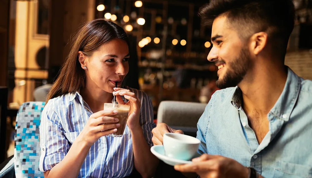 A man and woman are enjoying a conversation over drinks at a cozy caf