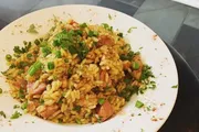 The image shows a plate of fried rice garnished with chopped green onions.