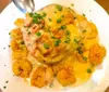 The image displays a plate of what appears to be a creamy seafood dish with shrimp and a garnish of chopped green onions served on a bed of fried or perhaps grilled items that could be vegetables or a type of fritter