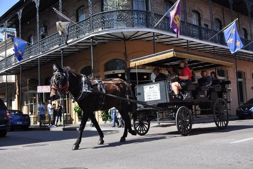 A horse-drawn carriage with passengers travels through a street lined with historic buildings and iron balconies