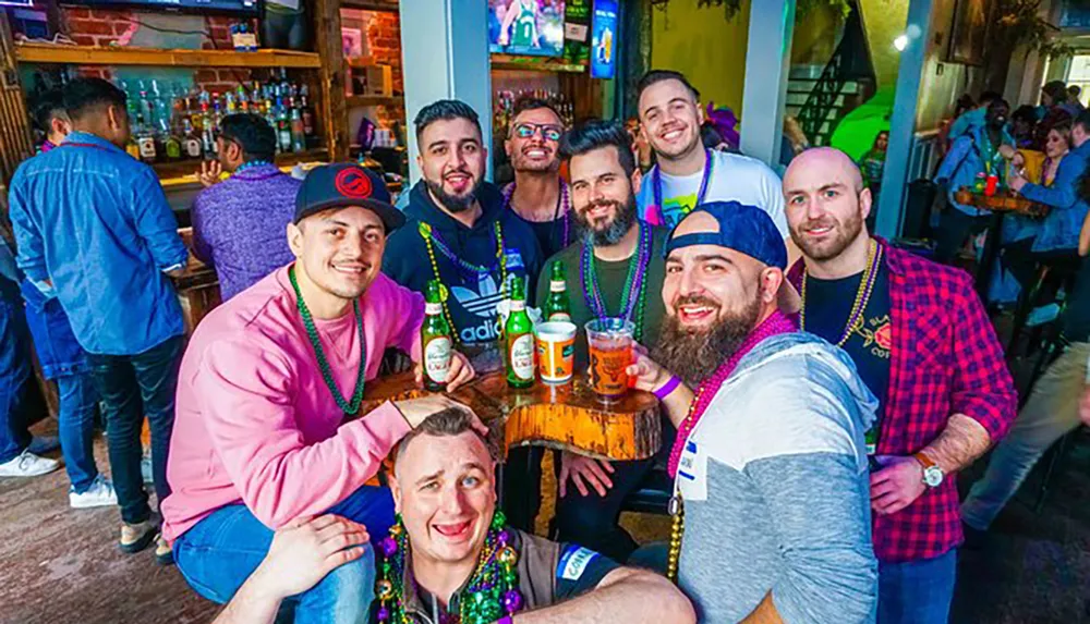 A group of happy friends wearing Mardi Gras beads is posing for a photo at a lively bar with drinks in hand