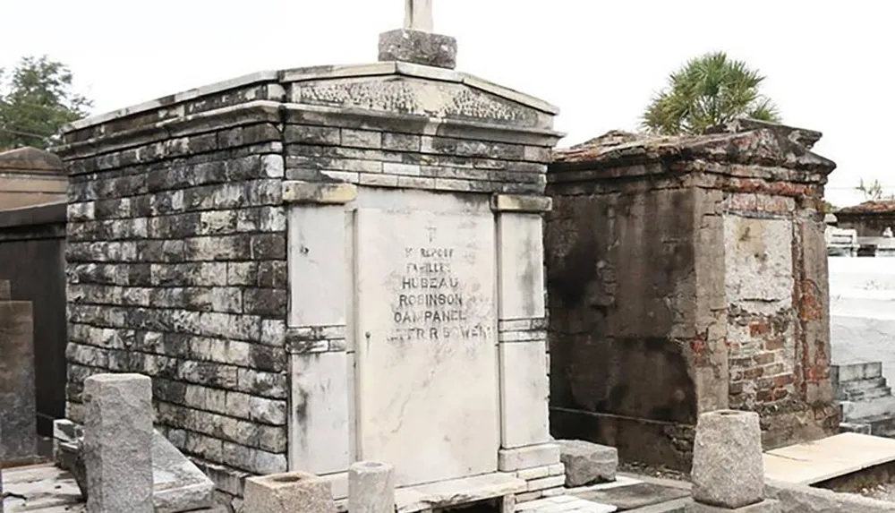 The image shows weathered above-ground tombs with inscriptions characteristic of a New Orleans cemetery