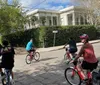 A group of four people are enjoying a leisurely bike ride on a sunny day in a residential neighborhood with lush greenery