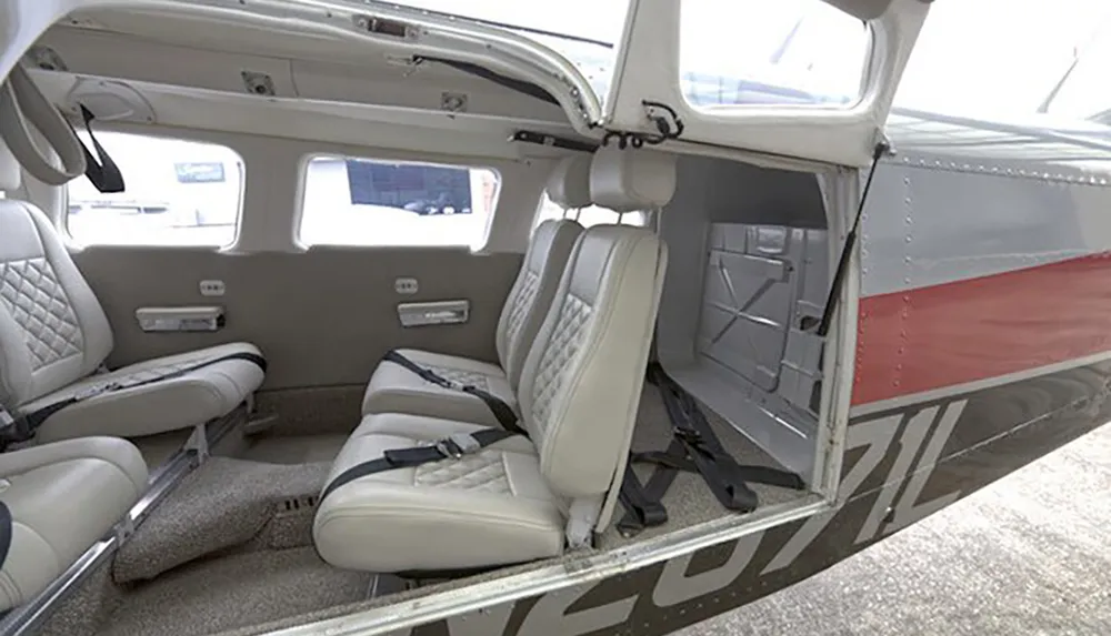 The image shows the interior of a small aircraft with a side door open revealing two rows of light-colored leather seats