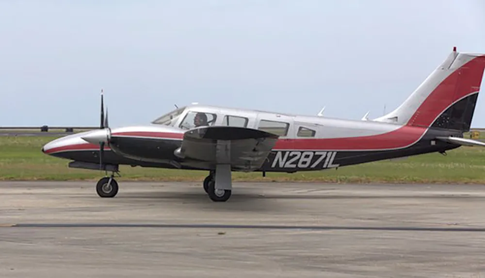 A red and white twin-engine aircraft with registration number N2871L is parked on a tarmac