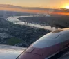The image captures a stunning sunset view from an airplane window showing the planes engine reflective wing and a meandering river below as the sun dips towards the horizon