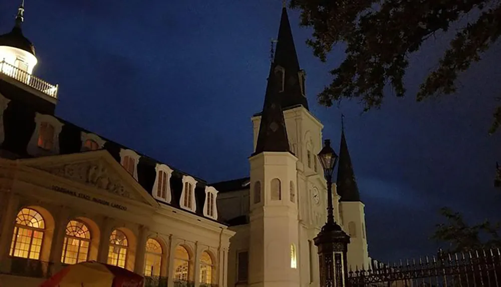 The image captures a serene twilight scene with the illuminated St Louis Cathedral in New Orleans standing against a dusky blue sky